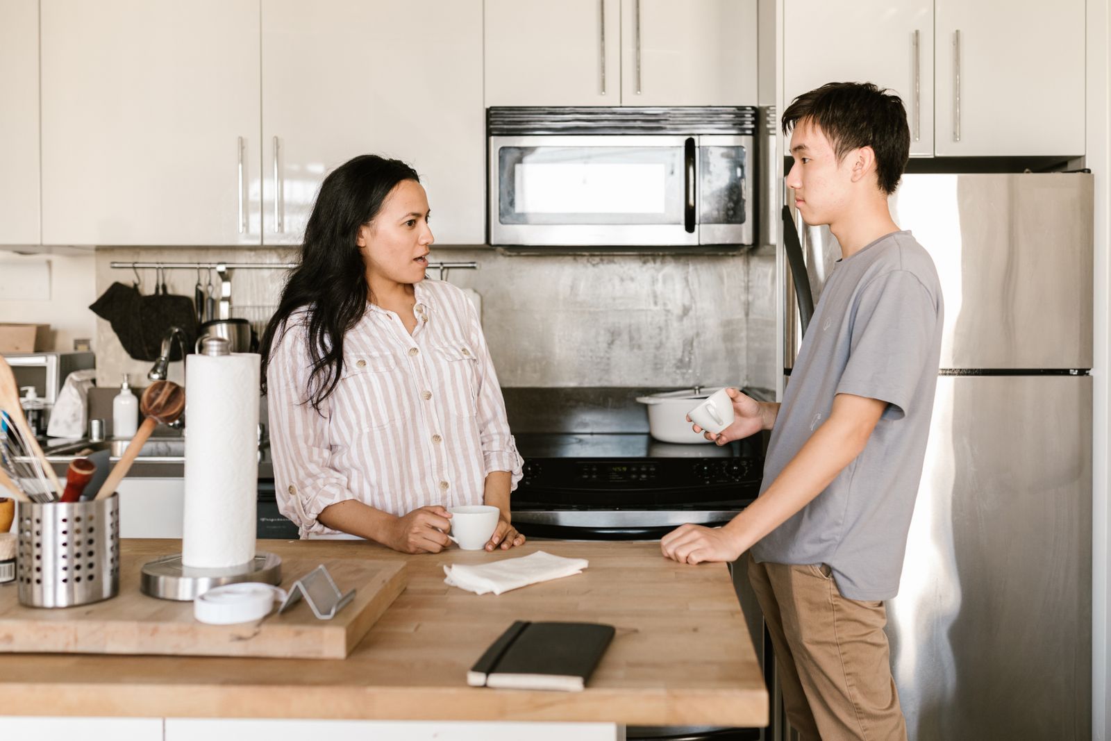 Two flatmates chatting over coffee in their kitchen